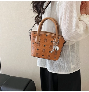 Détail du sac seau marron avec motif monogramme ours et breloque boule argentée
