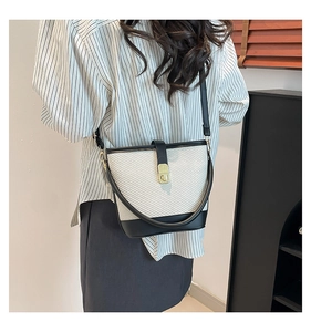 Detail of two-tone bucket bag featuring woven white texture and black leather trim