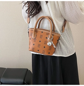Détail du sac seau en cuir marron avec motif d'ours et large bandoulière à motifs variés