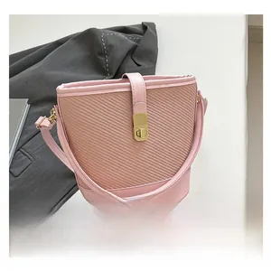 Détail macro du sac seau rose tissé avec cuir premium et fermoir rotatif doré élégant