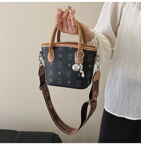 Détail d'un mini sac seau avec motifs d'ours, anses en cuir et larges bandoulières