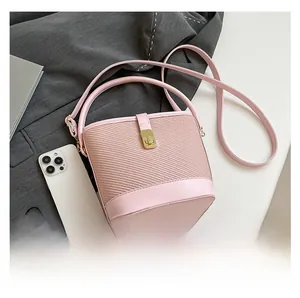 Détail du sac seau rose avec texture tissée et fermoir doré sur fond de veste de costume