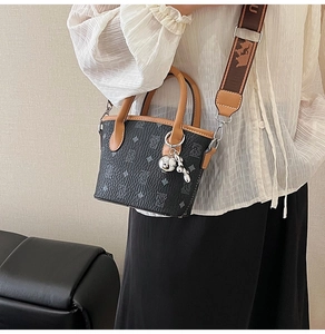 Détail du sac seau noir texturé avec finitions en cuir marron et bandoulière jacquard