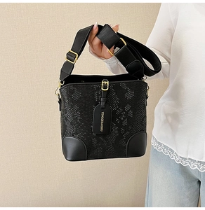 Detail of black snake-embossed bucket bag with wide strap and gold-tone hardware