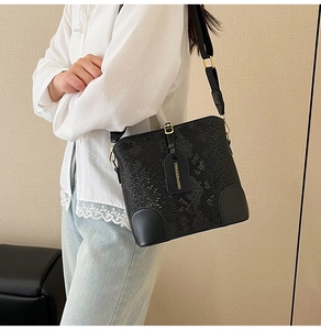Detail of black snake-textured bucket bag with adjustable wide strap and gold hardware