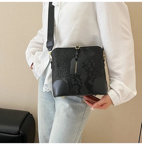 Detailed view of black snakeskin texture bucket bag with wide strap on a female model