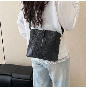 Detailed close-up of black crocodile texture leather bucket bag with golden buckle hardware