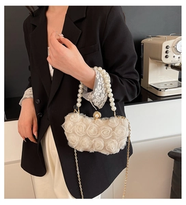 Close-up of 3D chiffon rose flowers and pearl handle on elegant cream white clutch