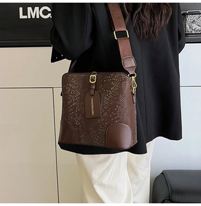 Detail of snake pattern texture on dark brown leather bucket bag with wide strap