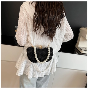 Detail of elegant black chiffon rose evening bag with pearl handle and gold chain