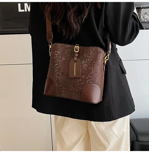 Macro shot of dark brown bucket bag with croc-embossed texture and gold metal buckle