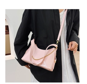 Detail of pink patent leather bag with gold chain strap on a model with black blazer