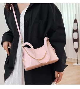 Detail of pink patent leather handbag featuring shiny finish and elegant gold chain strap