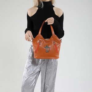Retro brown leather tote bag with metal cross and chain accessory shown on a model