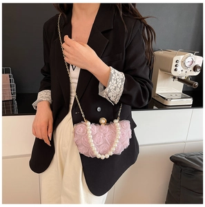 Detail of pink chiffon flower box bag with pearl handle and golden chain on a model