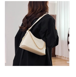 Detail view of cream bucket bag with glossy patent leather and gold chain strap