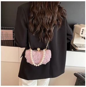 Detail of pink chiffon flower clutch bag with pearl strap on black blazer