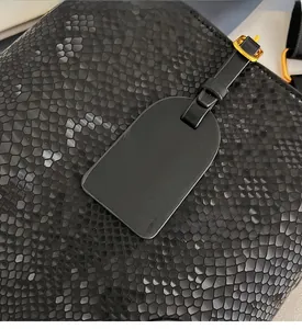 Detail of black snake pattern leather bucket bag with gold buckle and embossed tag