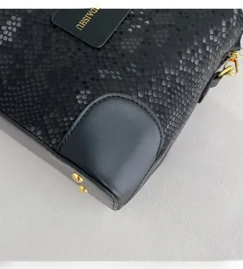 Detail of snake-embossed black leather bucket bag with golden metal protective studs