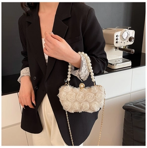 Detail of white chiffon floral evening bag with pearl handle and golden chain