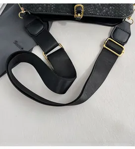 Detail of adjustable wide nylon shoulder strap with gold metal buckle on snake-pattern bag