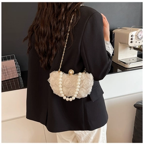 Close-up of 3D chiffon flower texture and pearl handle on cream evening clutch bag