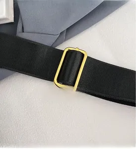Detail of premium gold metal adjustment buckle on black wide nylon shoulder strap