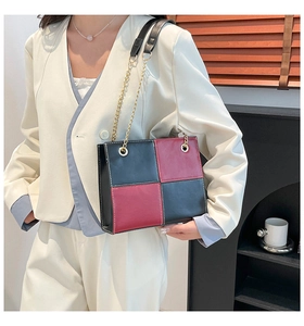 Detail of checkered crossbody bag with gold chain strap on model in office suit