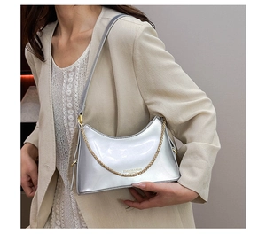 Detail of silver metallic shoulder bag with gold chain and smooth mirror finish
