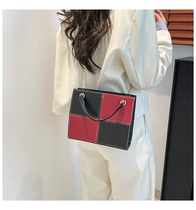 Modern red and black checkered crossbody bag with gold chain strap on white suit