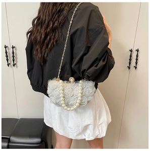Close-up of white chiffon flower evening bag with pearl handle and golden chain