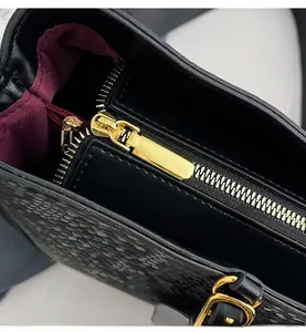 Detail of black embossed leather bucket bag showing gold hardware and burgundy lining