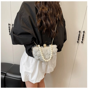 Detail of white chiffon floral evening bag with pearl handle and golden chain strap