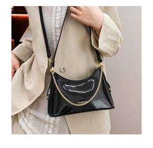 Detail of high-gloss black patent leather shoulder bag with golden chain and white logo