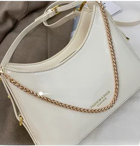 Detail of white patent leather bucket bag with chunky gold chain and fashion lettering