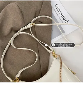 Detail of white patent leather bucket bag with gold chain strap on a brown blazer