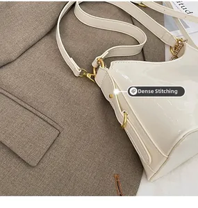 Close-up of precision stitching and gold hardware on white patent leather shoulder bag