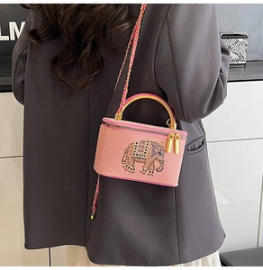 Detail of pink box bag featuring a sparkling elephant rhinestone pattern and golden handle