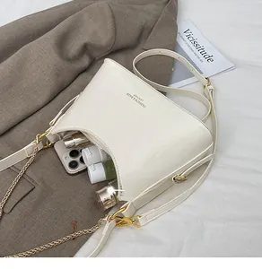 Interior capacity display of cream patent leather bag showing space for phone and makeup