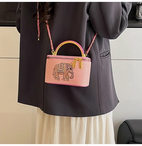Pink box clutch with crystal elephant detail and gold handle shown on a model