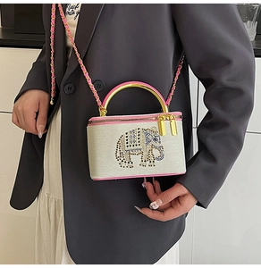 Detail of vanity box bag with rhinestone elephant pattern and gold metal handle