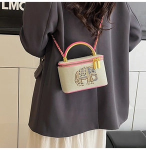 Detail of a beige box bag featuring a rhinestone elephant pattern and pink ring handle