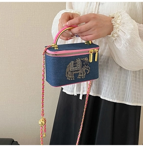 Close-up of denim box bag featuring a golden sequined elephant and pink leather chain strap