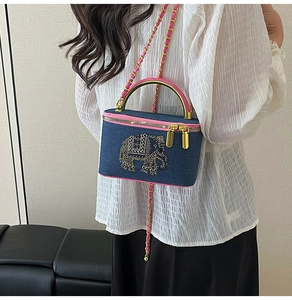 Detail of denim box bag with rhinestone elephant pattern and pink trim on model