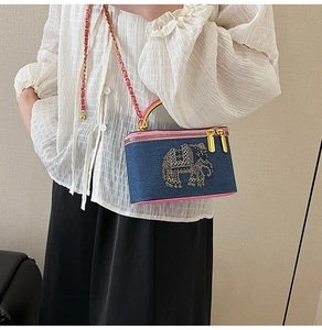 Detailed view of denim box bag featuring a rhinestone elephant and pink leather trim