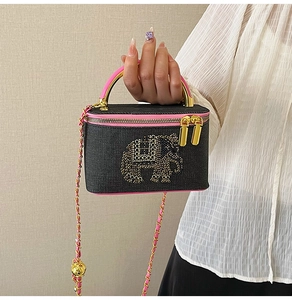 Macro view of denim box bag featuring rhinestone elephant and pink chain strap