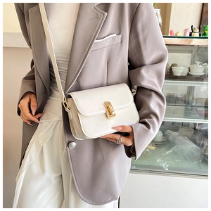 Detail of white textured leather shoulder bag with elegant gold twist lock and slim strap