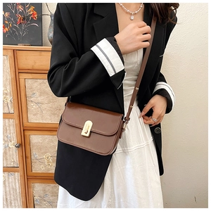Brown leather crossbody bag with golden rectangular lock shown on model with black blazer