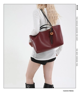 Detail of burgundy large tote bag featuring wood ring charm and slim black straps