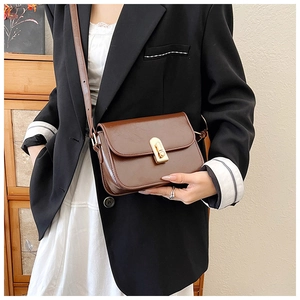 Detail of vintage brown leather crossbody bag with elegant golden rotary metal clasp